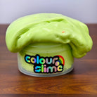 Green butter slime overflowing from a container labeled 'colour slime' on a wooden surface.