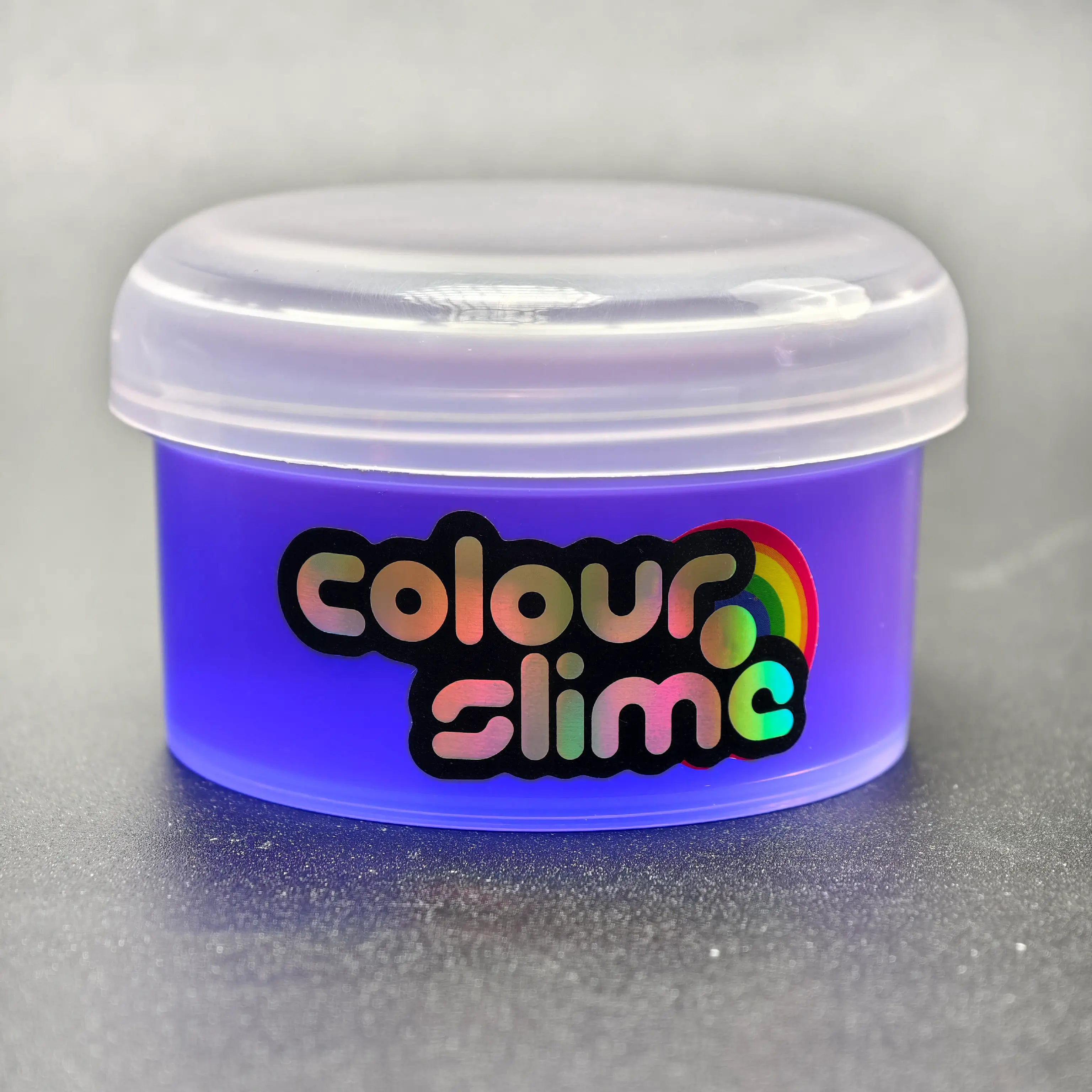Container of Colour Slime with a purple lid on a gray background